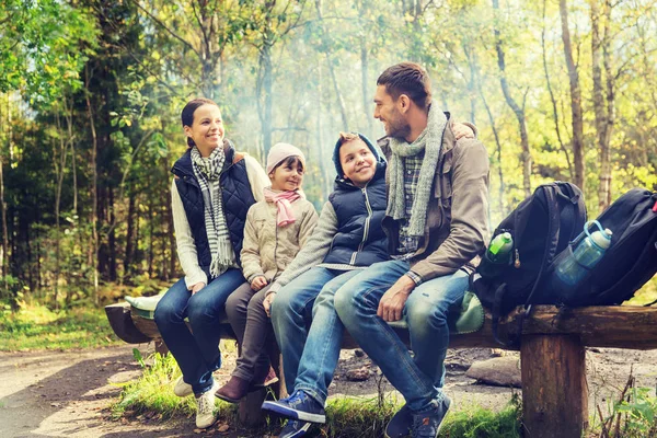 Happy family sitting on bench and talking at camp — Stock Photo, Image