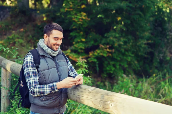 Gelukkig man met rugzak en smartphone outdoors — Stockfoto