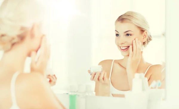 Boldog asszony krém alkalmazása arcát, fürdőszoba — Stock Fotó