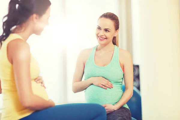 Zwei glückliche schwangere Frauen sitzen auf Bällen in der Turnhalle — Stockfoto