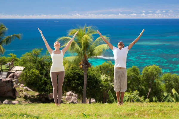 Gelukkige paar maken van yoga oefeningen op strand — Stockfoto