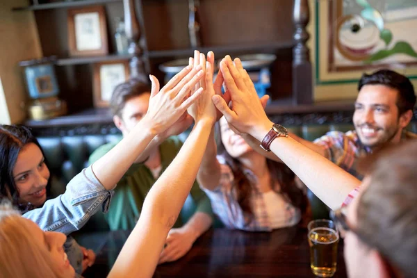 Друзья пьют пиво и дают пять в баре — стоковое фото