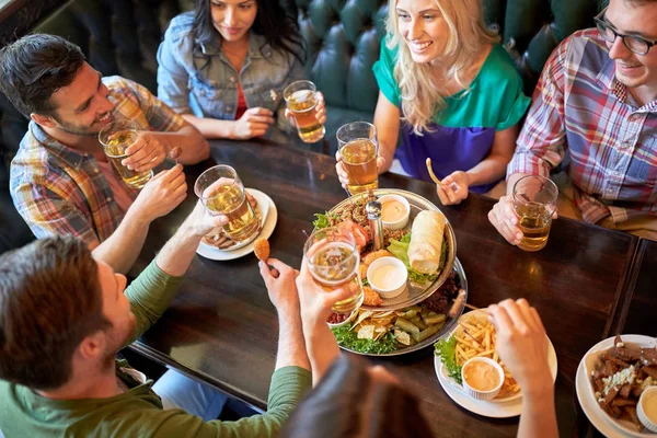 Щасливі друзі їдять і п'ють в барі або пабі — стокове фото