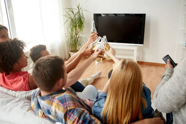 Друзья звонят в пиво и смотрят телевизор дома — стоковое фото