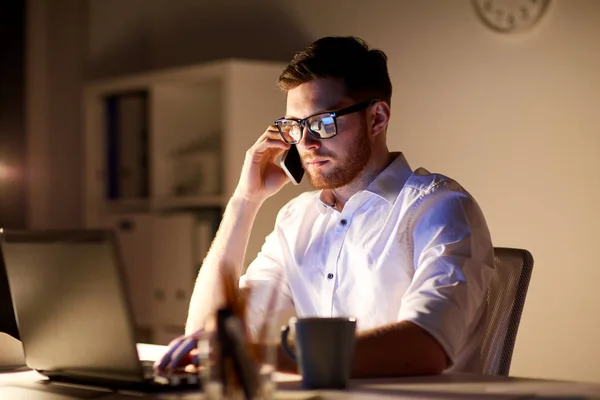 Homem de negócios chamando no smartphone no escritório da noite — Fotografia de Stock