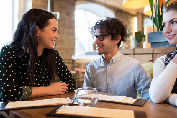 Happy friends with menu at restaurant — Stock Photo, Image