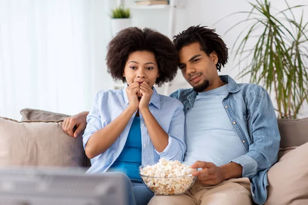 Feliz pareja con palomitas de maíz viendo la televisión en casa — Foto de Stock