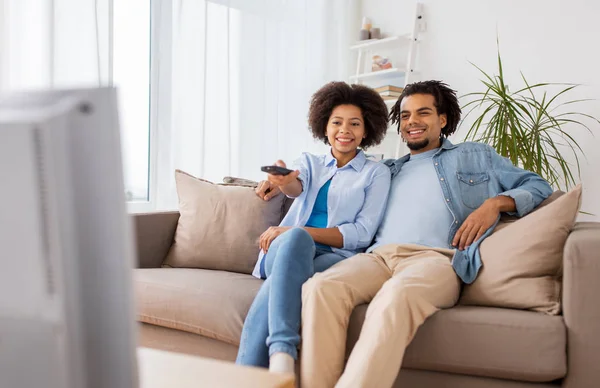 Sonriente pareja con control remoto viendo tv en casa — Foto de Stock