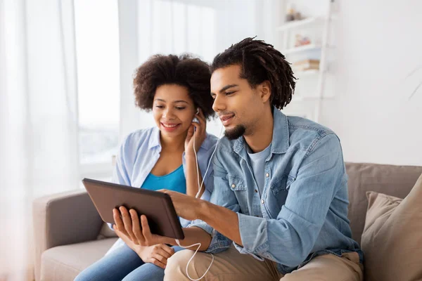 Casal feliz com tablet pc e fones de ouvido em casa — Fotografia de Stock