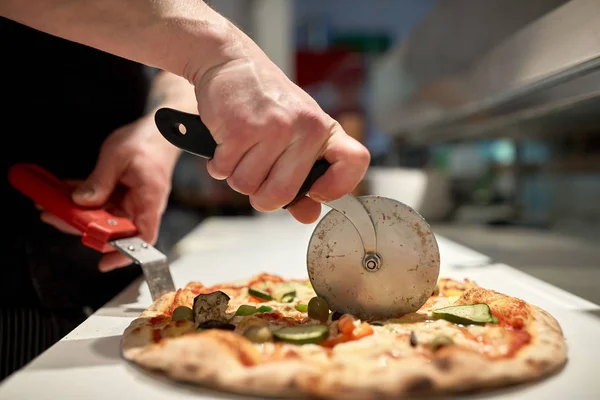 Варить разрезая пиццу на куски в пиццерии — стоковое фото