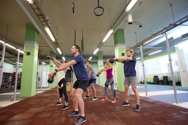 Grupo de pessoas com kettlebells se exercitando no ginásio — Fotografia de Stock