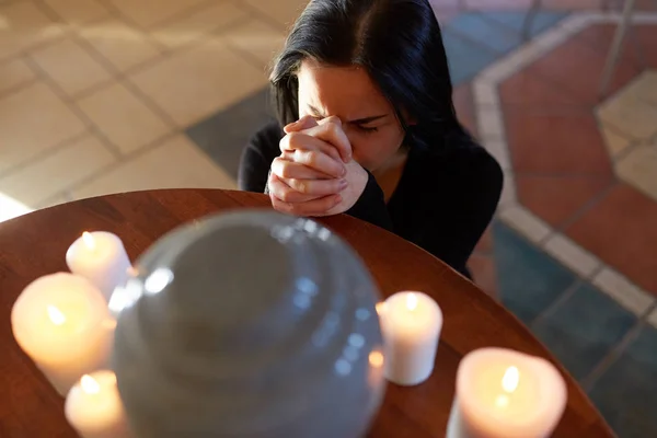 Mulher triste com urna funerária orando na igreja — Fotografia de Stock