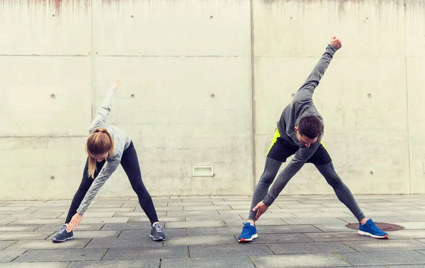 Close up of couple stretching on city street — Stock Photo, Image