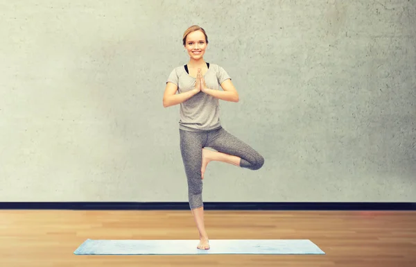 Женщина делает yoga в позе дерева на циновке — стоковое фото