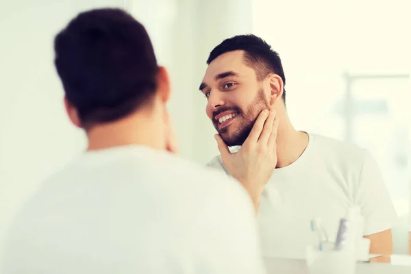 Gelukkig jonge man op zoek naar thuis badkamer spiegel — Stockfoto