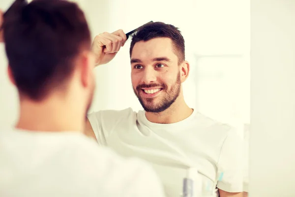 Šťastný muž kartáč na vlasy s hřebenem v koupelně — Stock fotografie