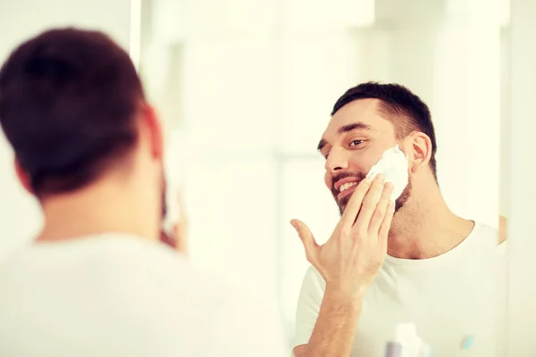 Щасливий чоловік застосовує піну для гоління у дзеркалі ванної кімнати — стокове фото