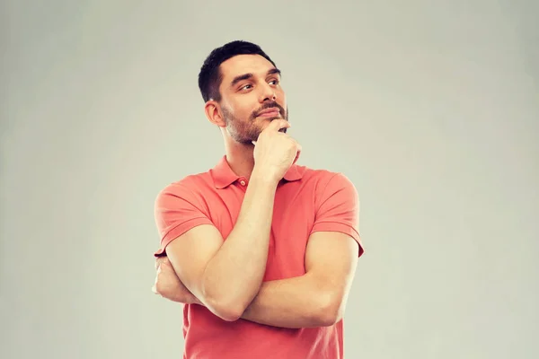 Mann im Polo-T-Shirt denkt über grauen Hintergrund nach — Stockfoto