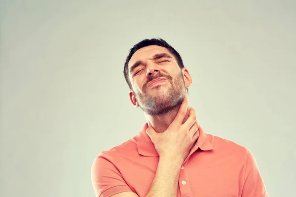 Чоловік торкається шиї і страждає від болю в горлі — стокове фото