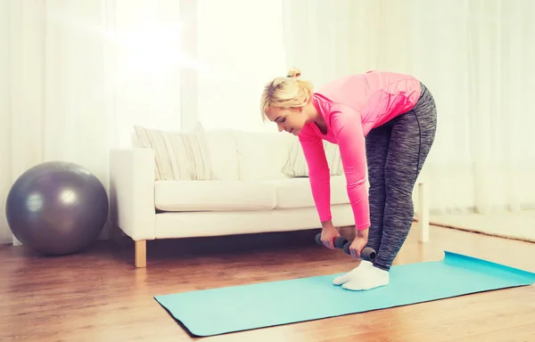 Lächelnde Frau mit Hanteln beim Training zu Hause — Stockfoto