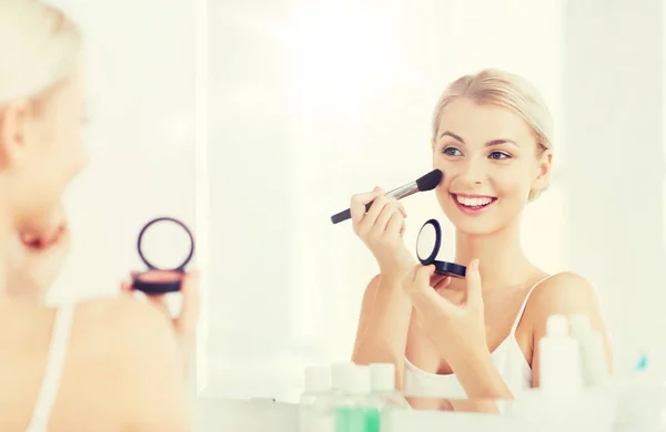 Mulher com escova de maquiagem e blush no banheiro — Fotografia de Stock