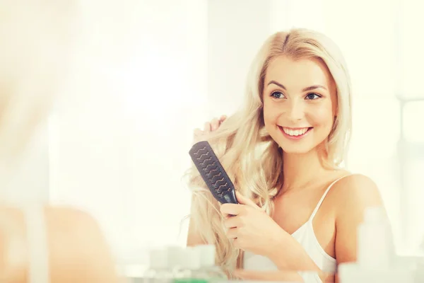 Mulher feliz escovar o cabelo com pente no banheiro — Fotografia de Stock