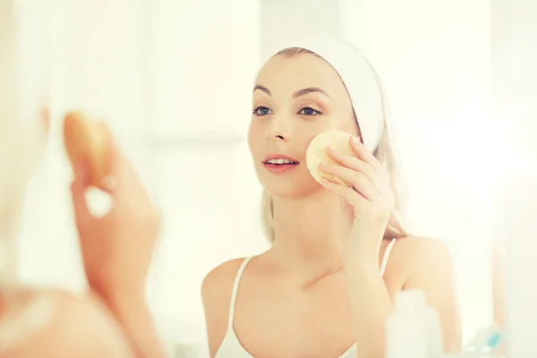Jovem mulher lavar rosto com esponja no banheiro — Fotografia de Stock