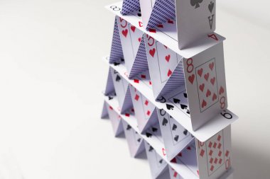 house of playing cards over white background clipart