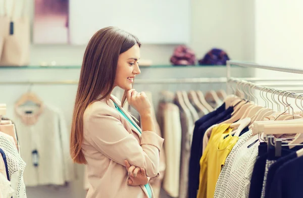Gelukkig jonge vrouw kleding in winkelcentrum kiezen — Stockfoto