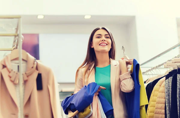 Feliz jovem mulher escolhendo roupas no shopping — Fotografia de Stock