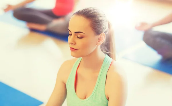 Ung kvinna att göra yoga och meditera i gym — Stockfoto