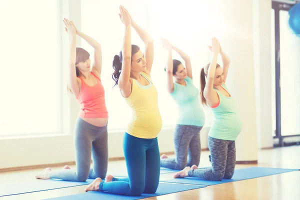 Glada gravida kvinnor utövar på mattor i gym — Stockfoto