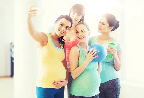 Mujeres embarazadas tomando selfie por teléfono inteligente en el gimnasio —  Fotos de Stock