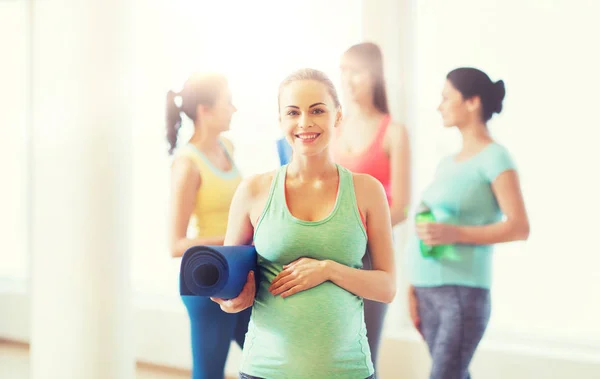 Mujer embarazada feliz con estera en el gimnasio — Foto de Stock