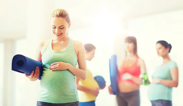 Mujer embarazada feliz con estera en el gimnasio — Foto de Stock