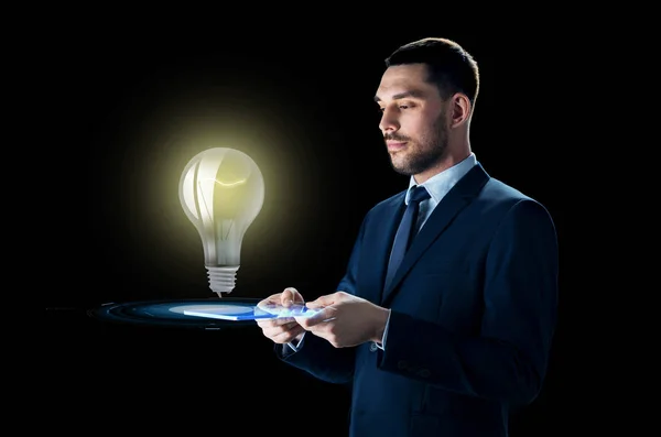 Uomo d'affari con tablet pc e lampadina — Foto Stock