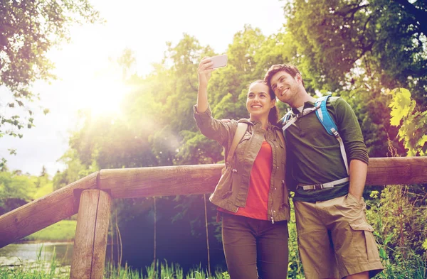 Couple with backpacks taking selfie by smartphone — Stock Photo, Image