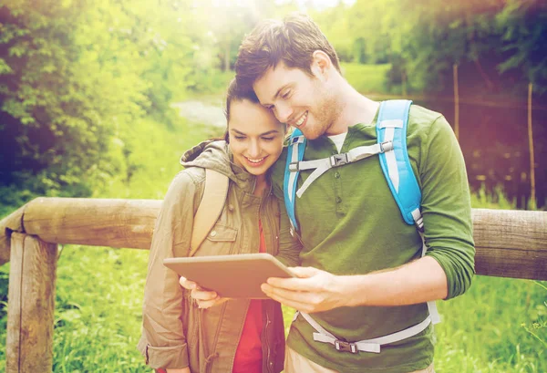 Feliz pareja con mochilas y tableta PC al aire libre — Foto de Stock