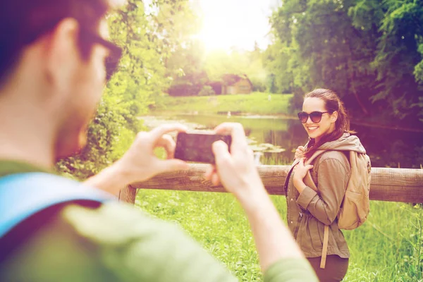 Couple with backpacks taking picture by smartphone — Stock Photo, Image