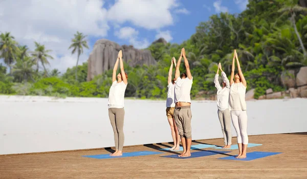 Gruppo di persone che fanno esercizi di yoga sulla spiaggia — Foto Stock