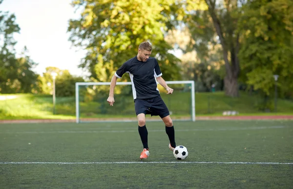 Joueur de football jouant avec le ballon sur le terrain de football — Photo