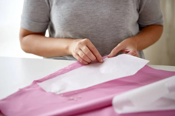 Woman with pins stitching paper pattern to fabric — Stock Photo, Image