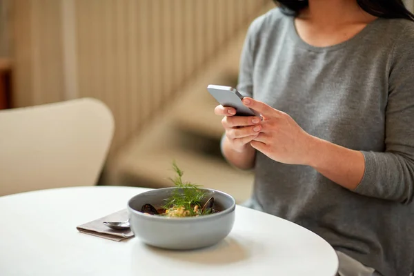 智能手机和碗汤在咖啡馆的女人 — 图库照片