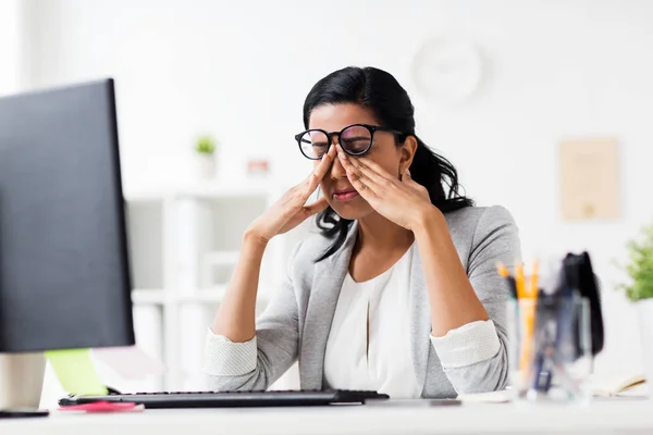 Businesswoman rubbing tired eyes at office — Stock Photo, Image
