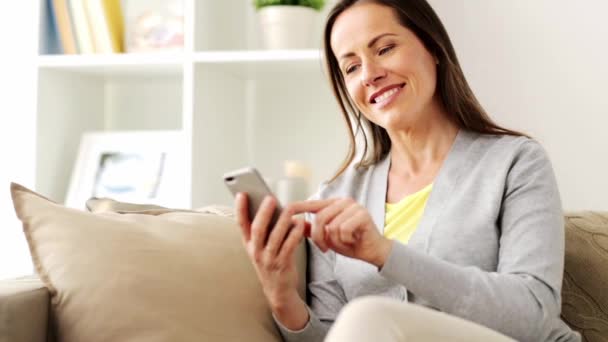 Счастливая женщина смс-ки на смартфоне дома — стоковое видео