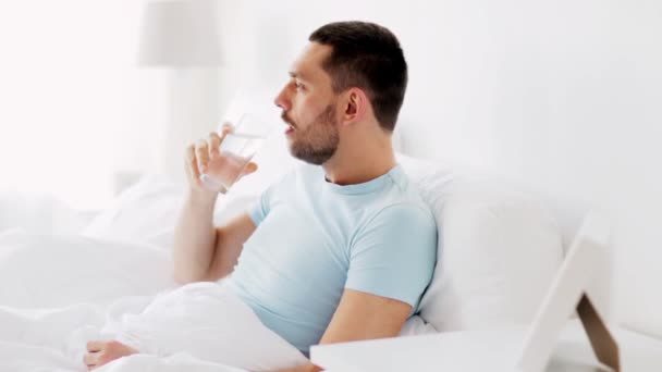Hombre beber agua en la cama en casa — Vídeo de stock