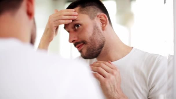 Happy young man looking to mirror at home bathroom — Stock Video