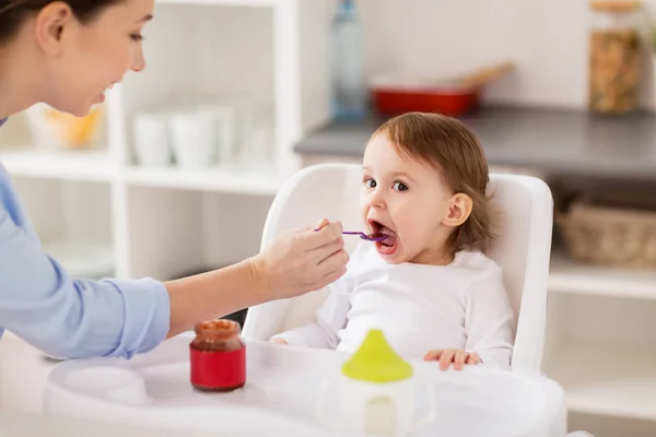 Szczęśliwy matka karmienie dziecko z puree w domu — Zdjęcie stockowe