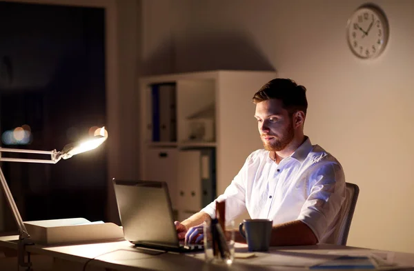 Бизнесмен, сидящий на ноутбуке в ночном офисе — стоковое фото