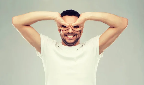 Mann bastelt Fingerbrille vor grauem Hintergrund — Stockfoto